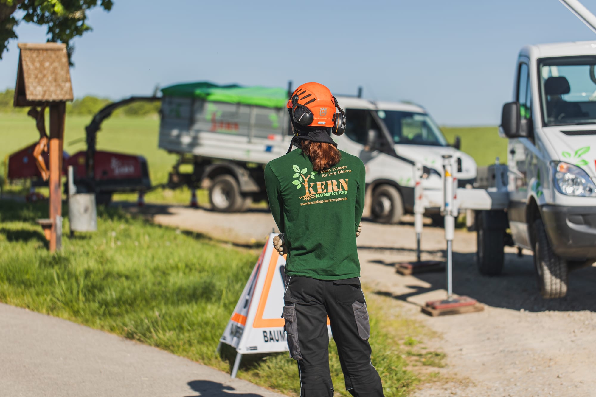 Baumpfleger mit Helm am Einsatzfahrzeug